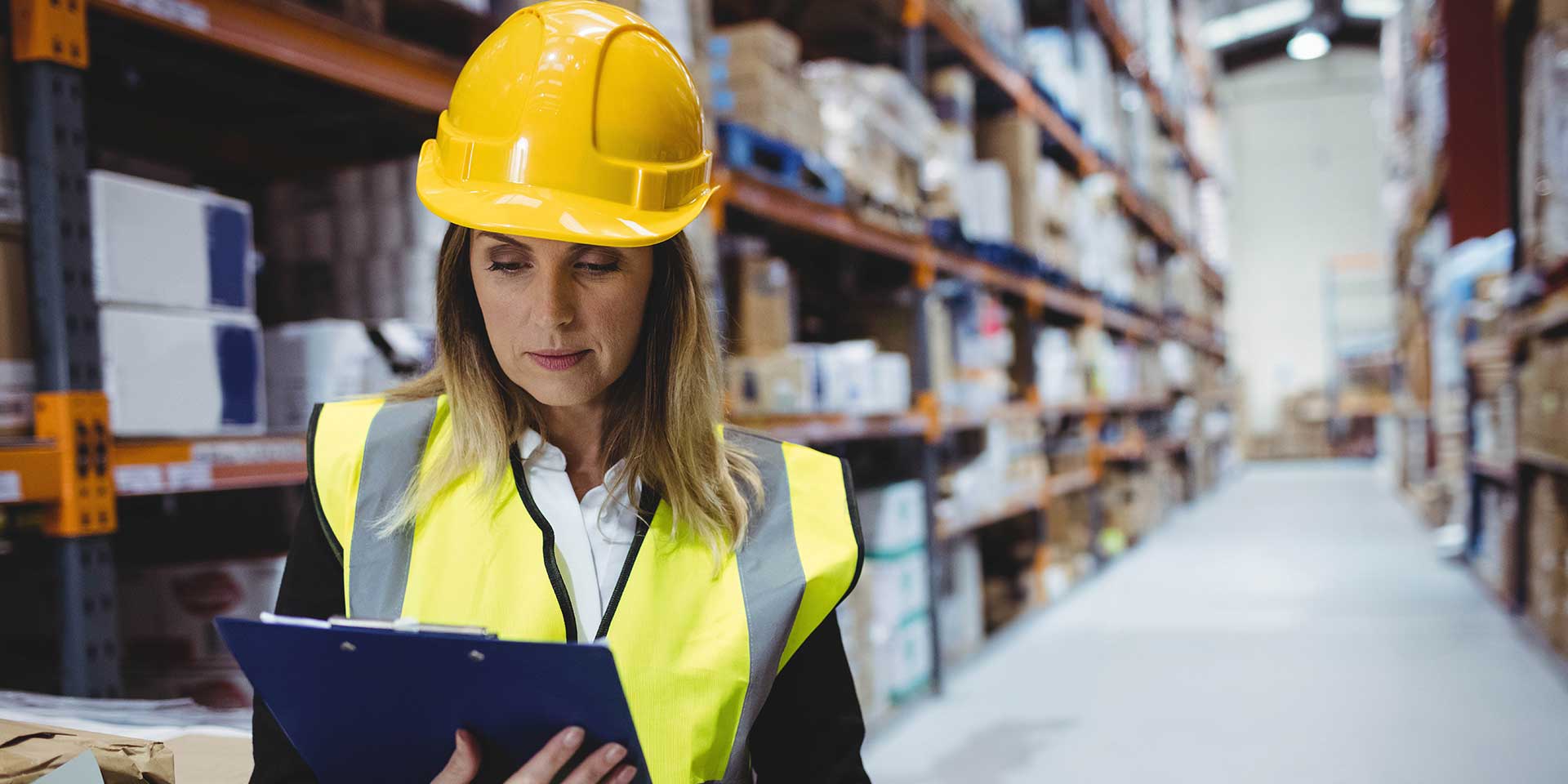 hero-erfassungsbogen Frau in Sicherheitskleidung füllt im Lager Erfassungsbogen Arbeitsschutz.