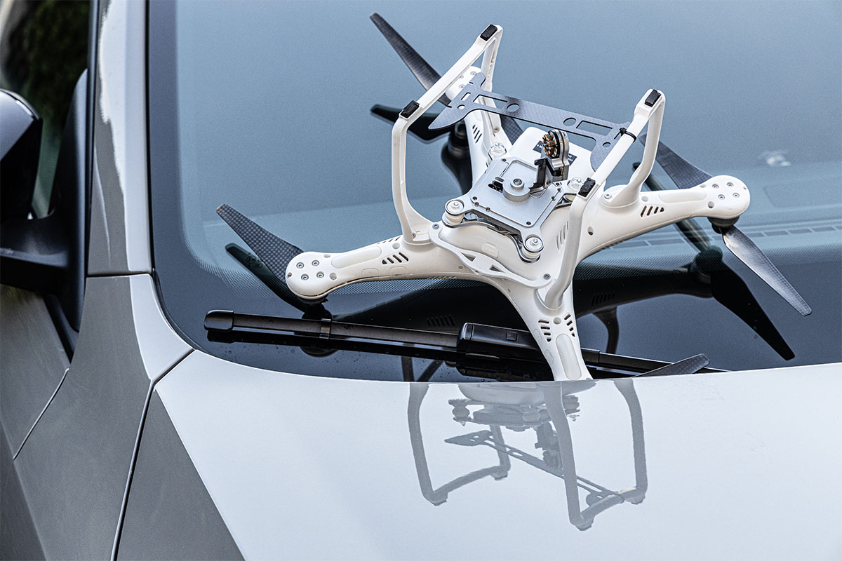 Abgestürzte Drohne liegt auf der Motorhaube eines Autos und zeigt mögliche Sachschäden durch Drohneneinsatz.