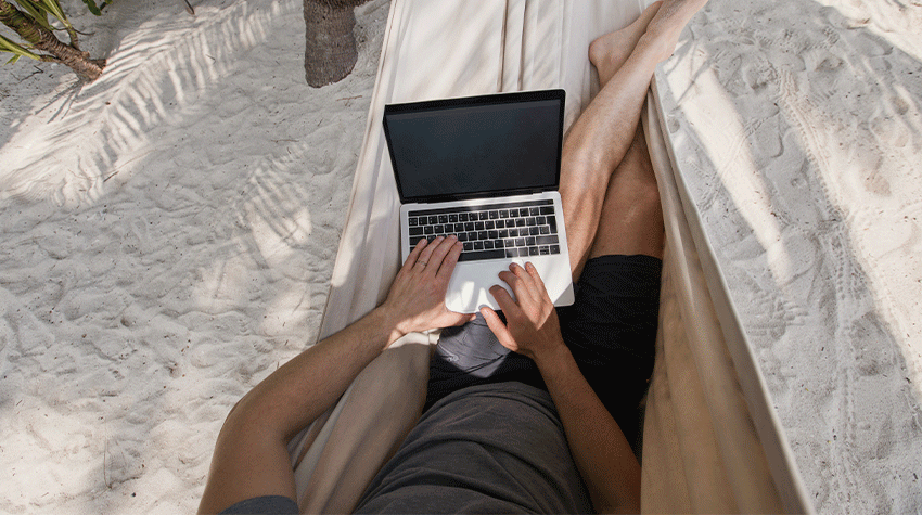 Mann arbeitet während seiner Workation in einer Hängematte mit Laptop am Strand. © Adobe Stock, Song_about_summer 